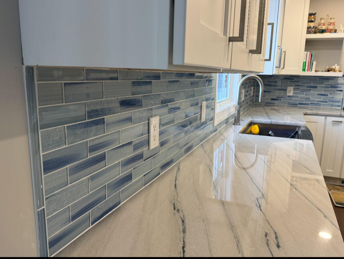 Blue tile backsplash along light kitchen countertop and sink Blue tile backsplash along light kitchen countertop and sink