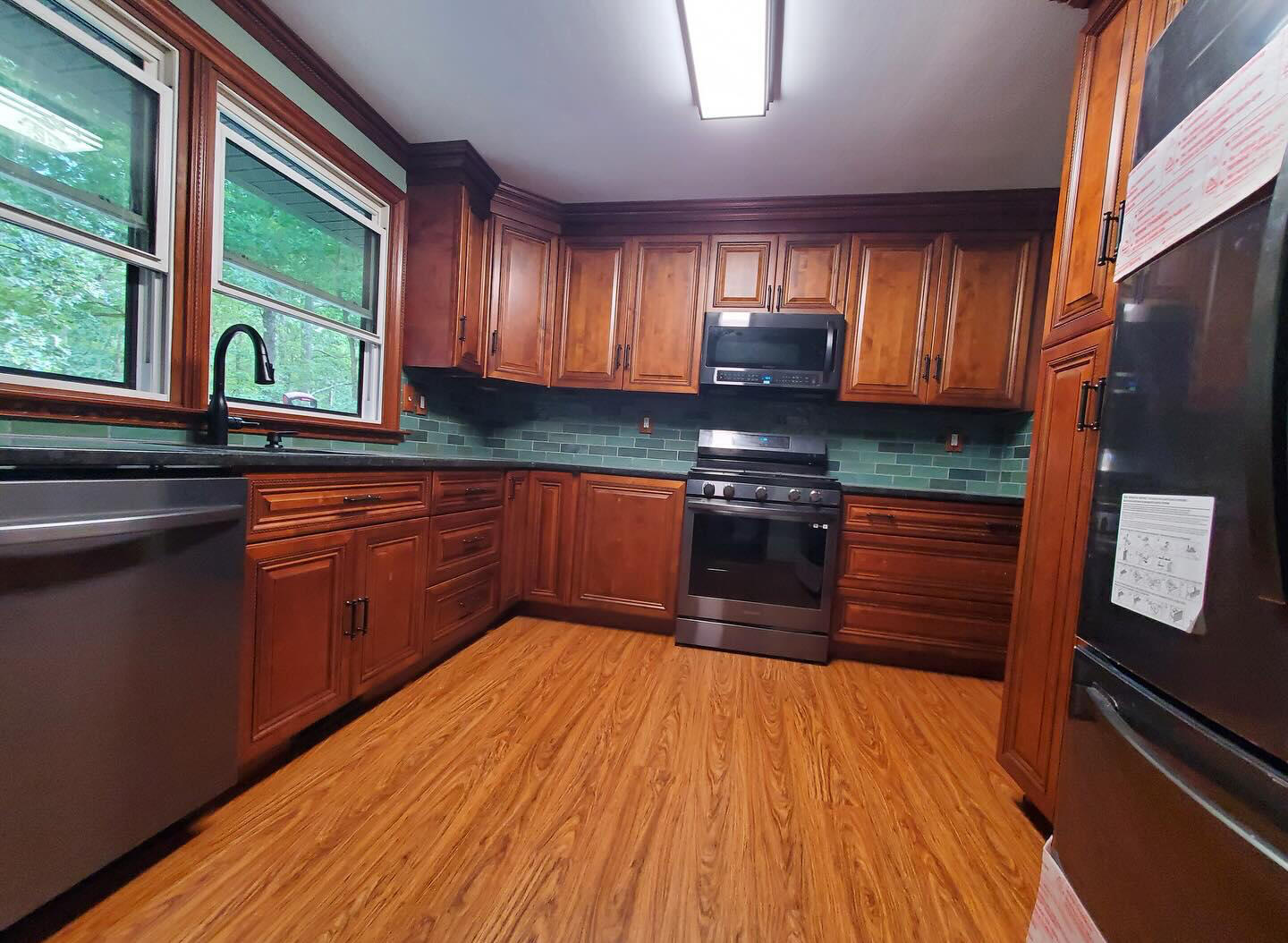 Finished kitchen with wood cabinets, green tile backsplash and stainless appliances