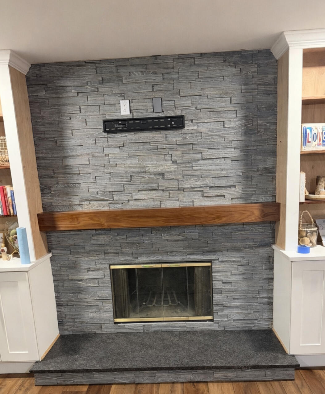 Finished gray stacked-stone fireplace surround with wood mantel