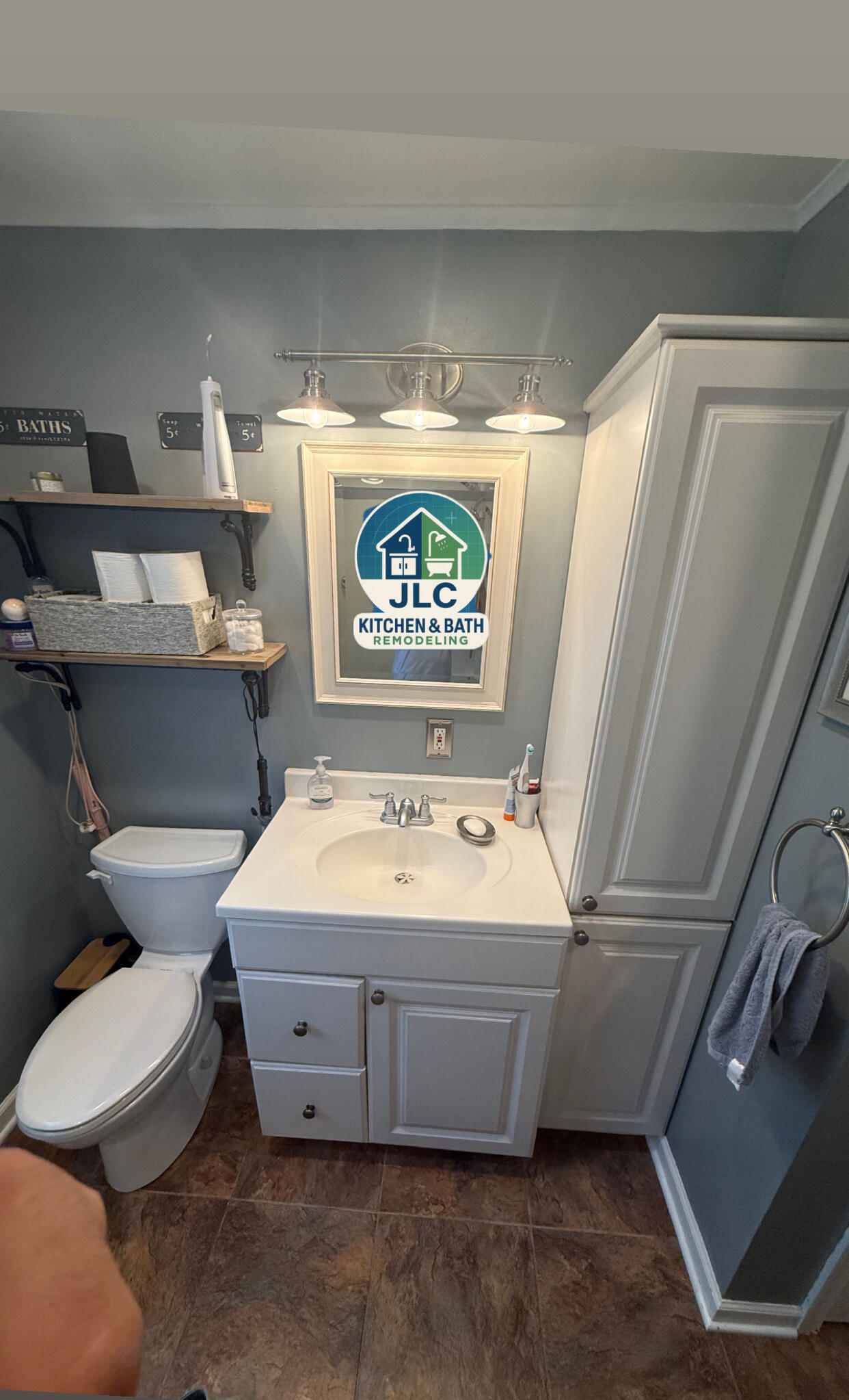 Bathroom vanity with white cabinet, framed mirror and three-light fixture